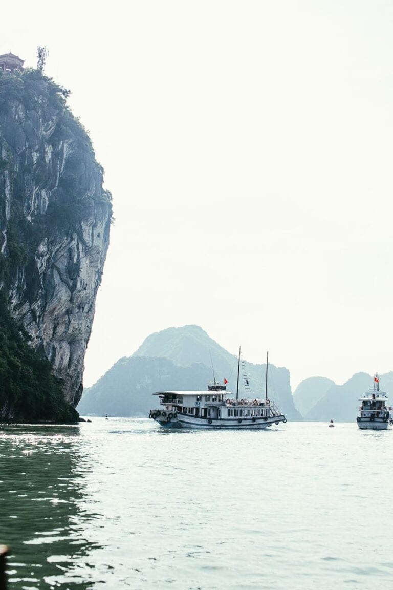 boats sailing on body of water near rock mountain